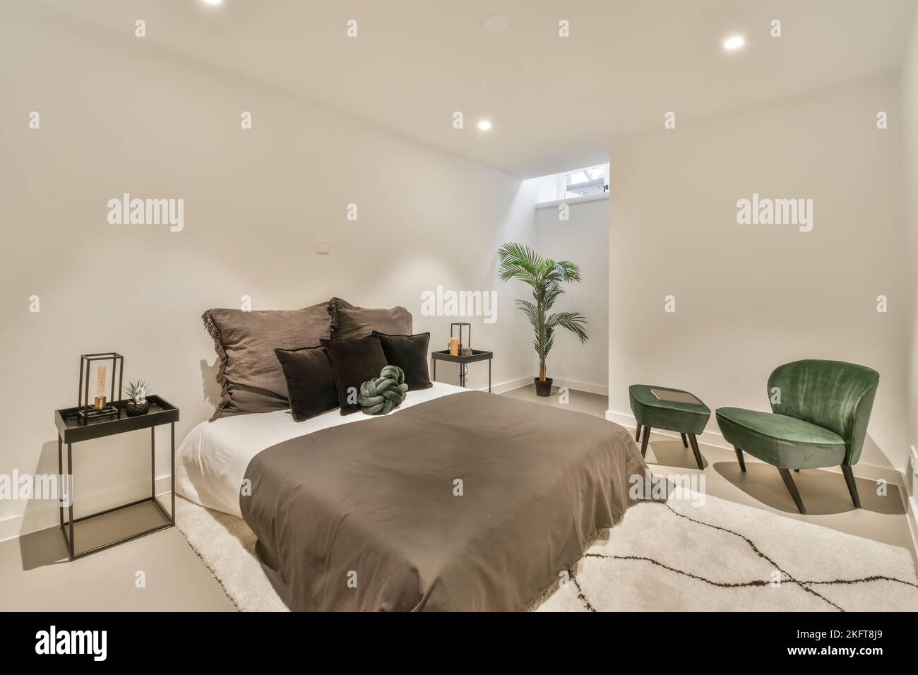 Komfortables Bett neben einem grünen Sessel und Teppichboden Stockfoto