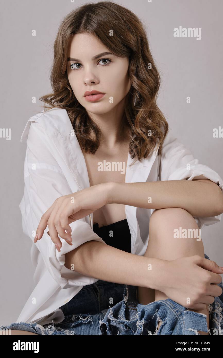 Porträt einer schönen, modernen Frau in weißer Bluse, Posen auf weißem Hintergrund Stockfoto