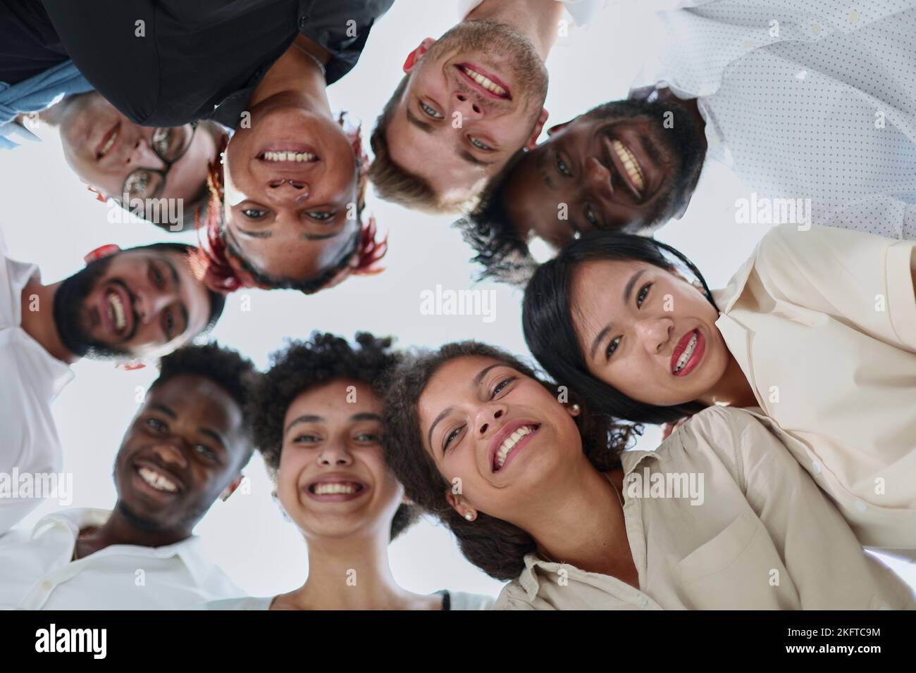 Eine Gruppe verschiedener junger Menschen, die im Kreis stehen und nach unten schauen Stockfoto