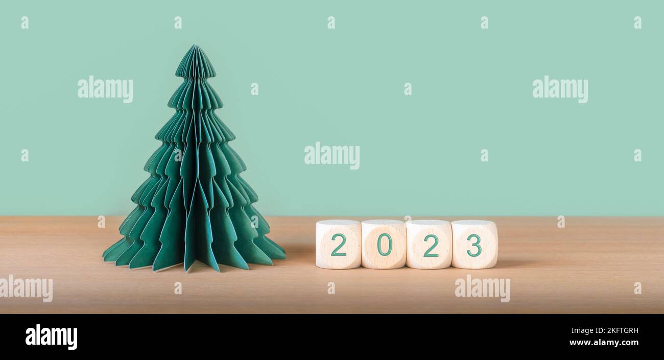 Holzwürfel mit der Jahresnummer 2023 in der Nähe von Papier als Weihnachtsbaumschmuck. Stockfoto