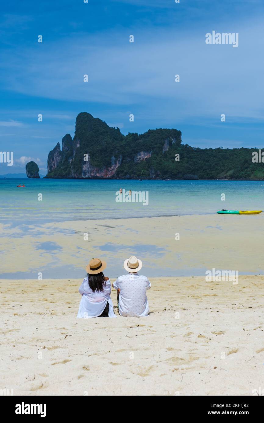 Koh Ph Phi Thailand, ein paar Männer und Frauen sitzen am Strand in der Morgensonne. Loh Dalum Beach Koh Phi Phi Stockfoto