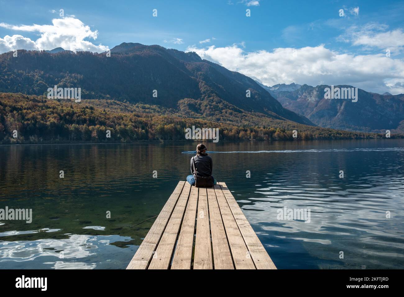 Sitzen auf einem kleinen Steg und genießen den Blick auf die Landschaft des Bohinjer Sees im Triglav Nationalpark, den Julischen Alpen, Slowenien Stockfoto