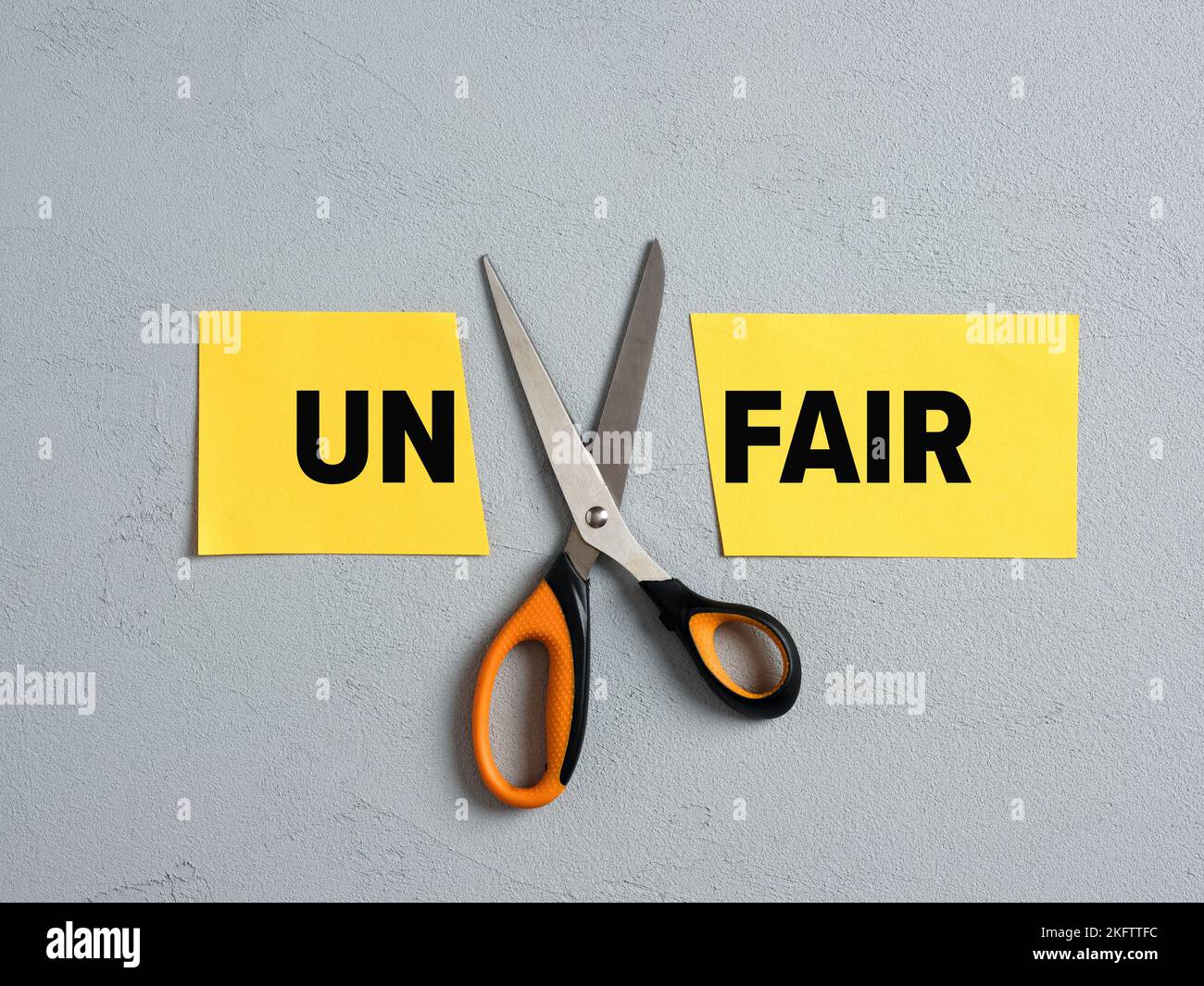 Schere schneidet das Wort UN von unfair ab. Konzept von Fairness, Gleichheit, Gerechtigkeit und Integrität. Stockfoto