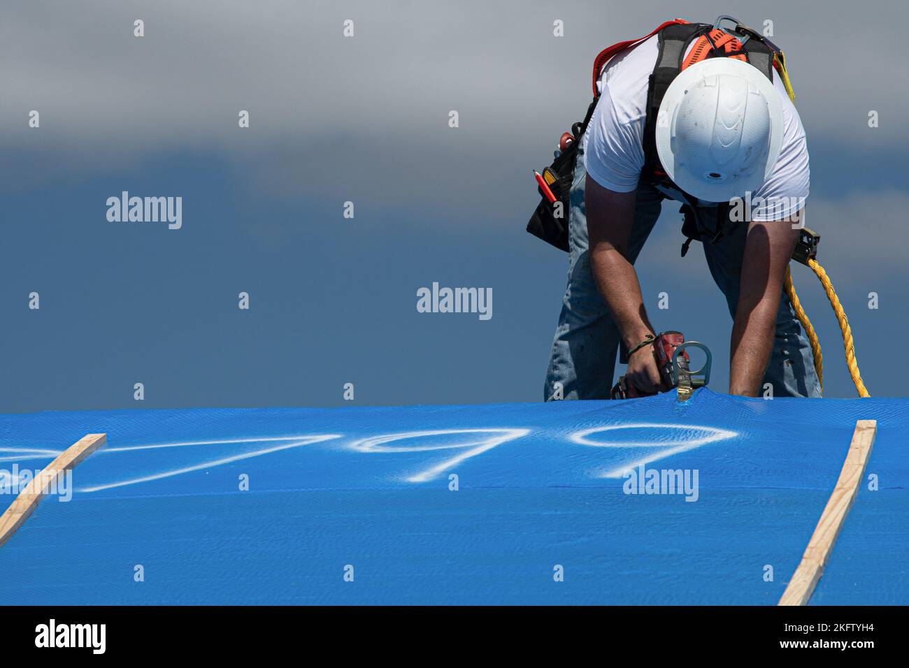 Samstag, 8. Oktober 2022, die erste Blue Roof Installation in Fort Myers, Florida. Der Dachdecker Jonathan Whitaker entfernt den D-Ring. Operation Blue Roof wurde entwickelt, um Eigentum zu schützen, die temporären Wohnungskosten zu senken und es den Bewohnern zu ermöglichen, während sie sich vom Sturm erholen. Ein Bewohner beginnt mit der Einreichung eines Einreiseantrags (ROE) über die Website blueroof.us oder telefonisch unter 888-ROOF-BLU (888-766-3258). Stockfoto