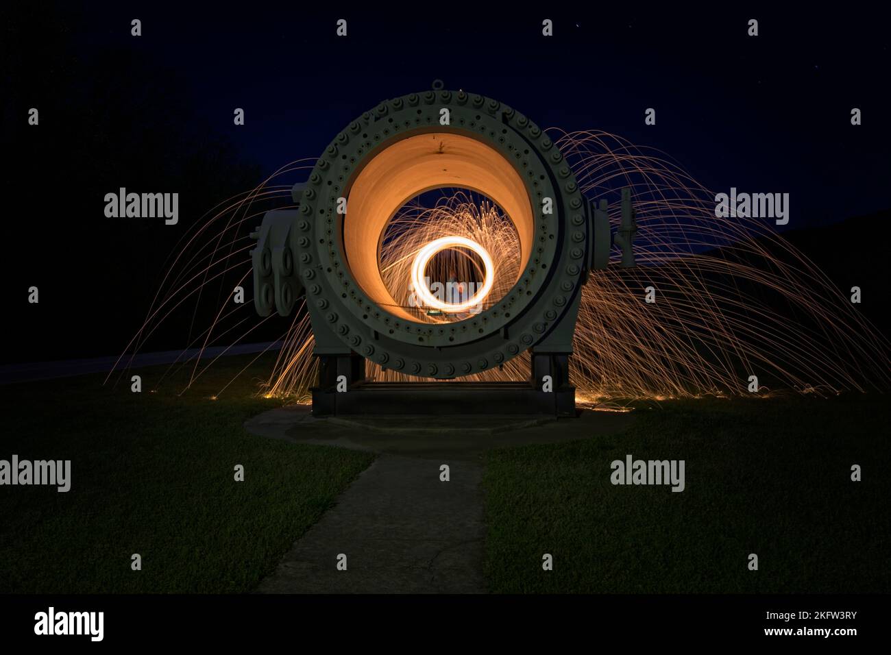 Eine hige runde Metallröhre auf einem Grasgarten mit Firlelights in der Nacht Stockfoto