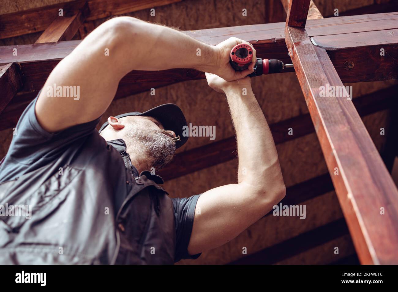 Handwerker bohrt ein Loch in den hölzernen Türrahmen. Renovierung des Hauses Stockfoto