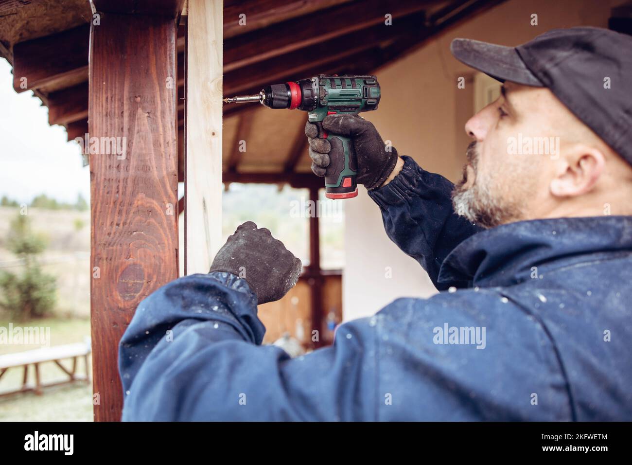 Handwerker bohrt ein Loch in den hölzernen Türrahmen. Renovierung des Hauses Stockfoto