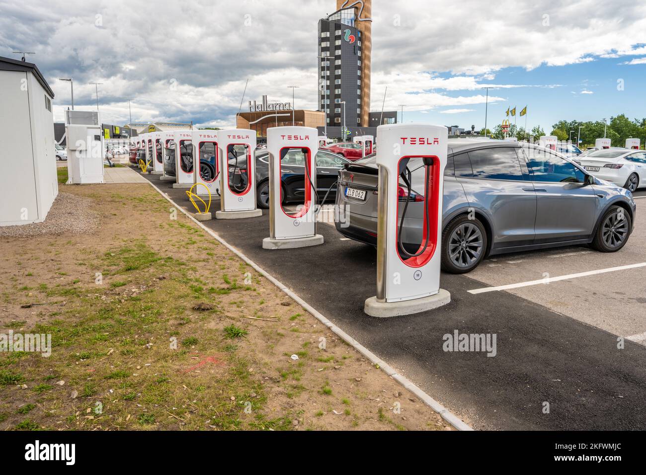 Halmstad, Schweden - Juli 10 2022: Lange Reihe von Tesla-Autos laden beim Tesla Supercharger Halmstad Stockfoto