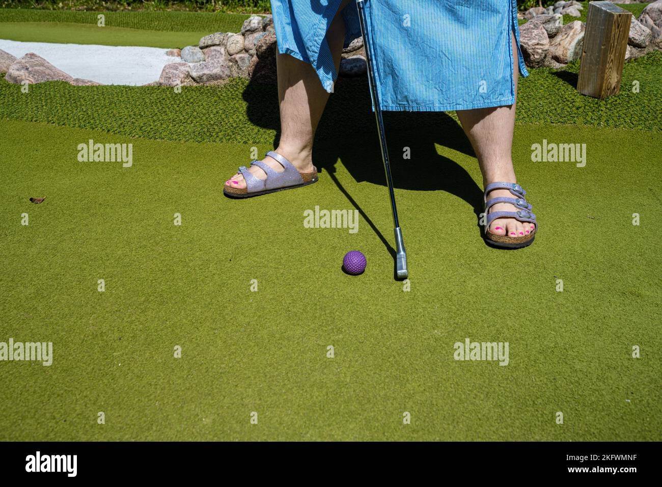 M?lndal, Schweden - Juli 17 2022: Frau spielt Minigolf mit einem violetten Ball Stockfoto