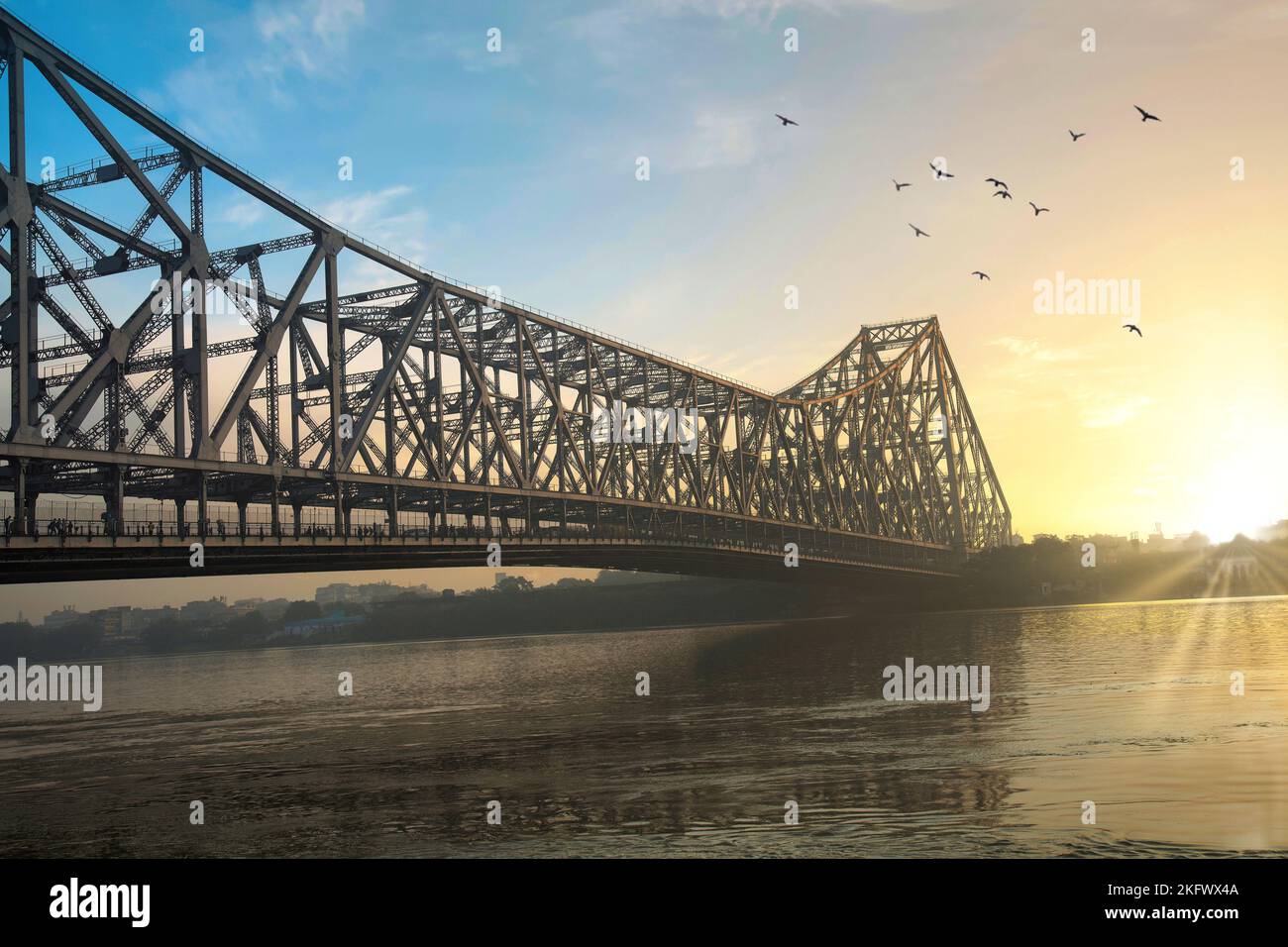 Howrah-Brücke bei Sonnenaufgang. Eine berühmte Kragarmbrücke am Ganges, die die Stadt Kalkutta mit dem Stadtteil Howrah verbindet. Stockfoto Howrah-Brücke bei Sonnenaufgang. Eine berühmte Kragarmbrücke am Ganges, die die Stadt Kalkutta mit dem Stadtteil Howrah verbindet. Stockfoto