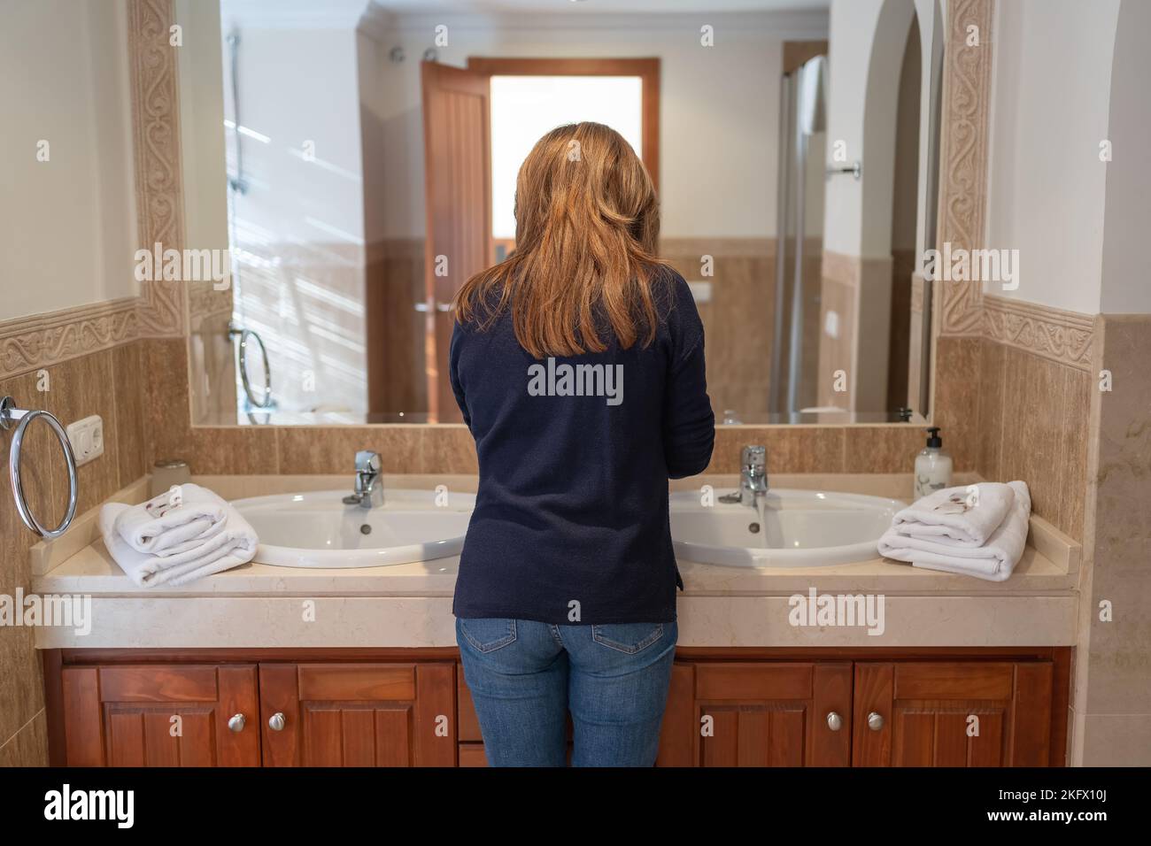 Frau, die sich in einem großen luxuriösen Badezimmer ihrer Ferienwohnung bereit machte. Stockfoto