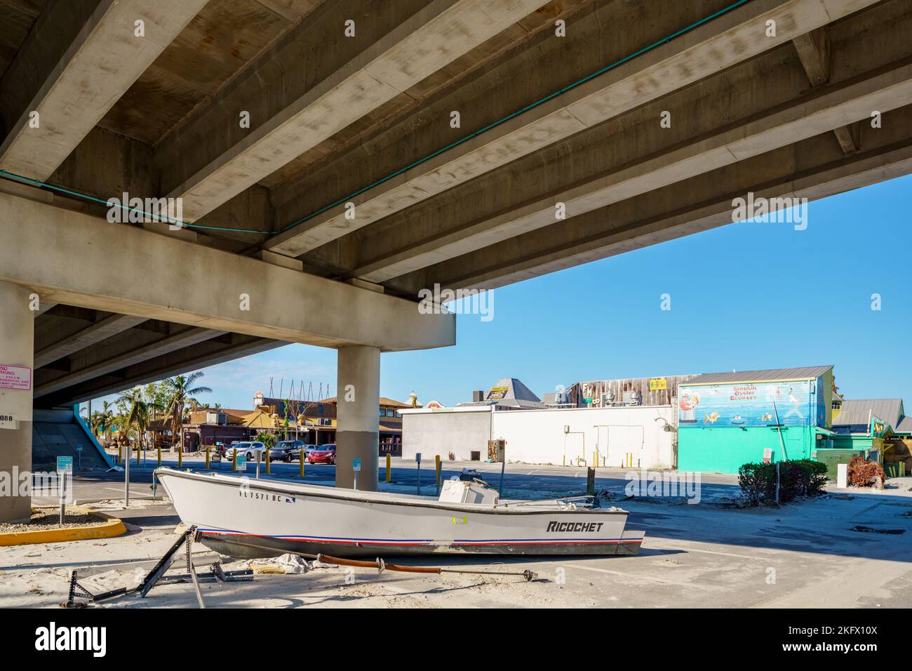 Fort Myers Beach, FL, USA - 19. November 2022: Das Boot driftete auf einen Parkplatz unter der Brücke, auf dem sich der Unwettern des Unweters Ian befindet Stockfoto