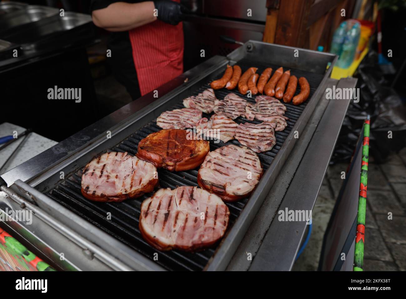 Details zu geringer Schärfentiefe (selektiver Fokus) mit Schweinewurst und Steaks, die auf einem Barbecue-Grill auf einem europäischen Bauernmarkt in Bukarest zubereitet werden Stockfoto