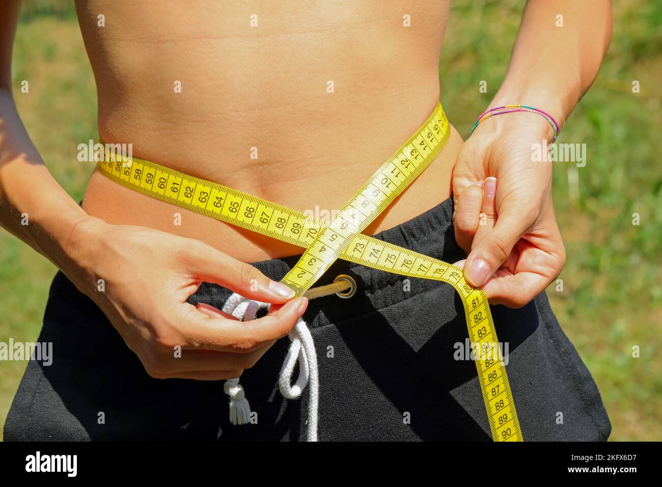 Mädchen misst ihre Taille mit einem gelben flexiblen Band Maßnahme während einer Schlankheits-Diät Stockfoto