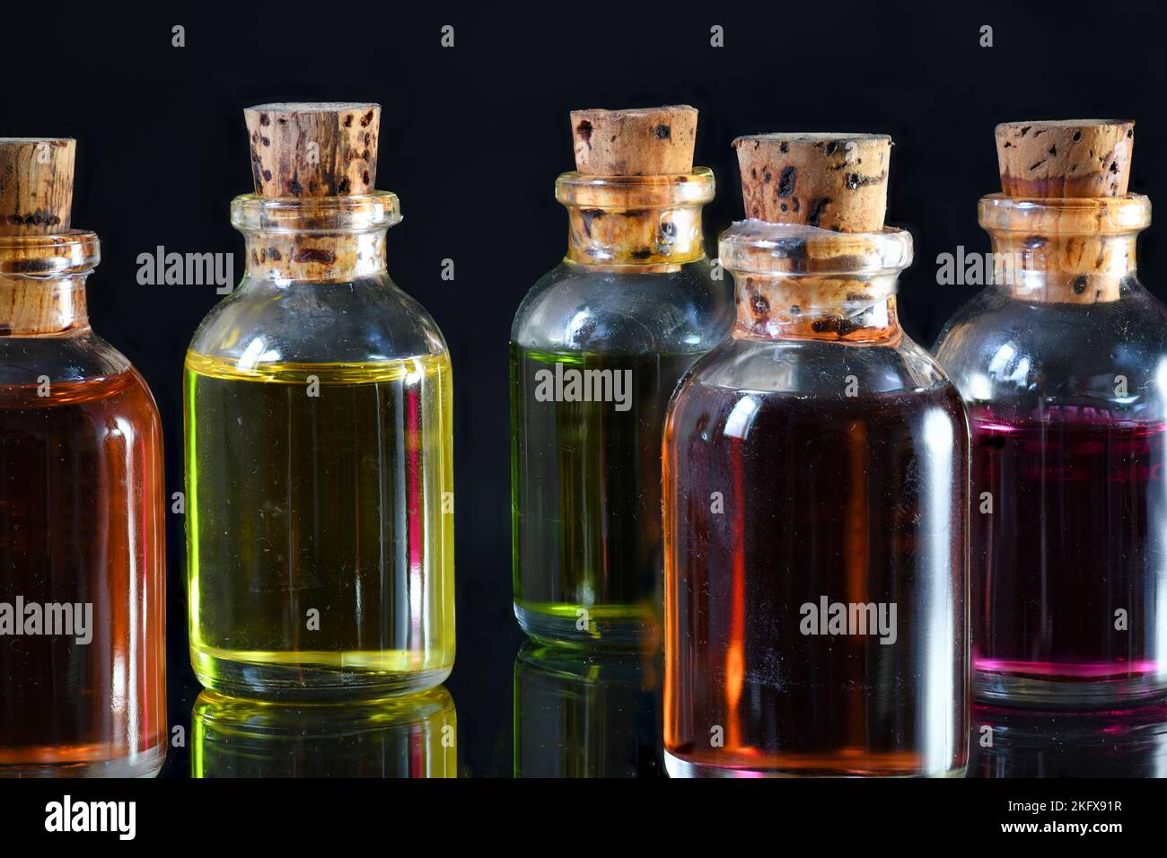Farbige Ölflaschen auf schwarzem Hintergrund Stockfoto