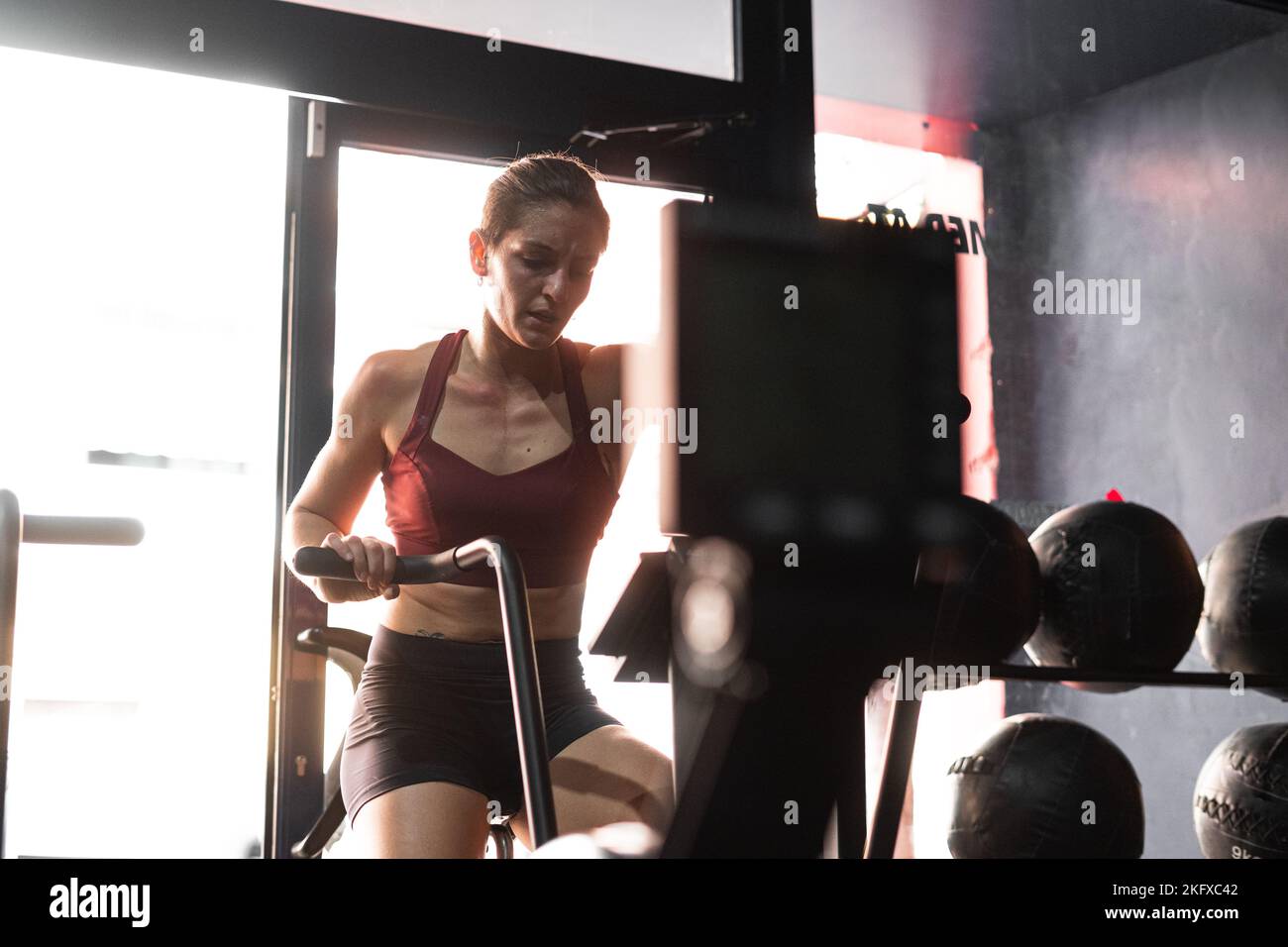 Brünette kaukasische Mädchen in einem roten Top Sport auf einem Heimtrainer in einem Fitnessstudio Stockfoto