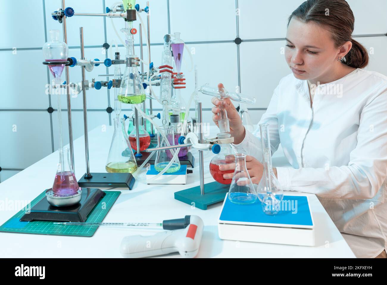 Chemisches Experiment im Labor für organische Chemie der Technischen Universität richtet eine junge Studentin einen Kolben zum Verdampfen von Flüssigkeit ein Stockfoto