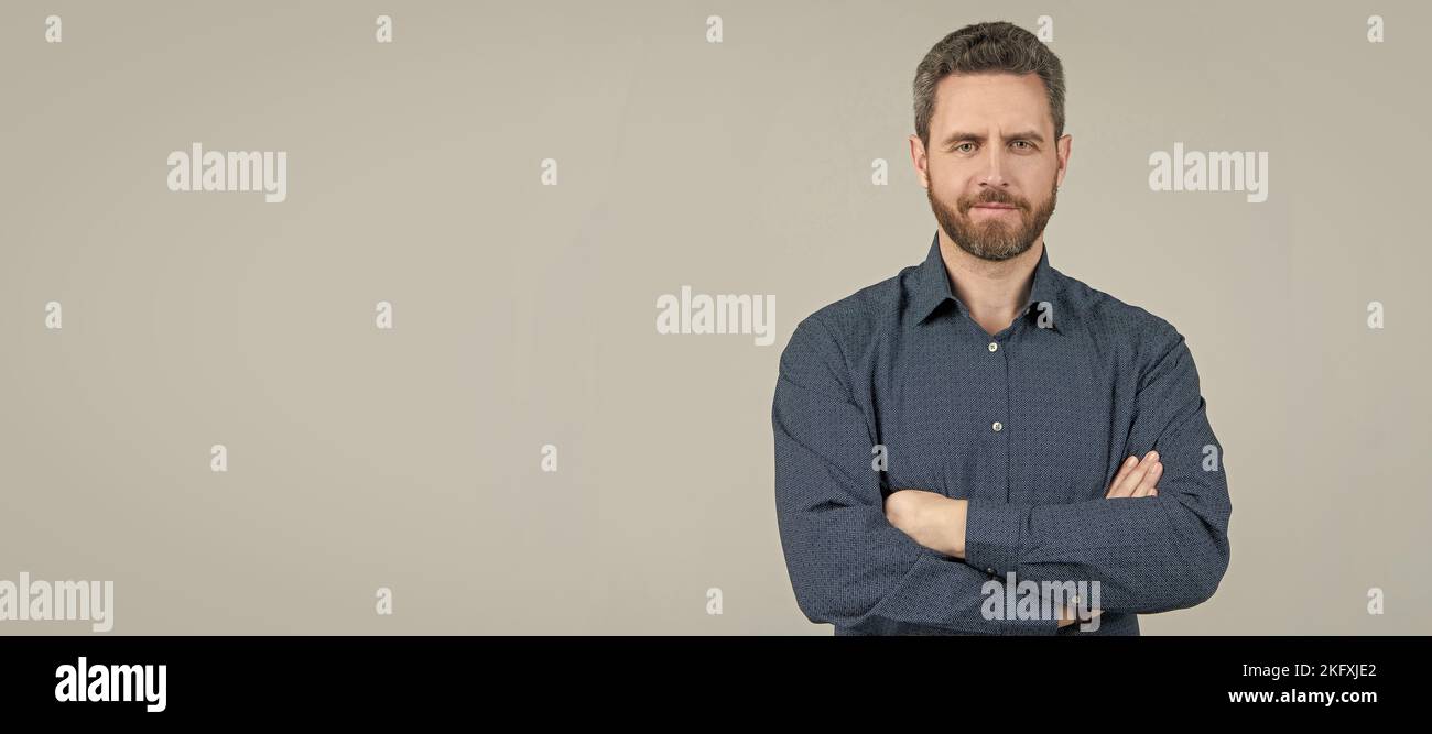 Selbstbewusster Mann trägt legeres Hemd mit gekreuzten Armen auf grauem Hintergrund, informelle Kleidung, Kopierraum. Mann Gesicht Porträt, Banner mit Copyspace. Stockfoto