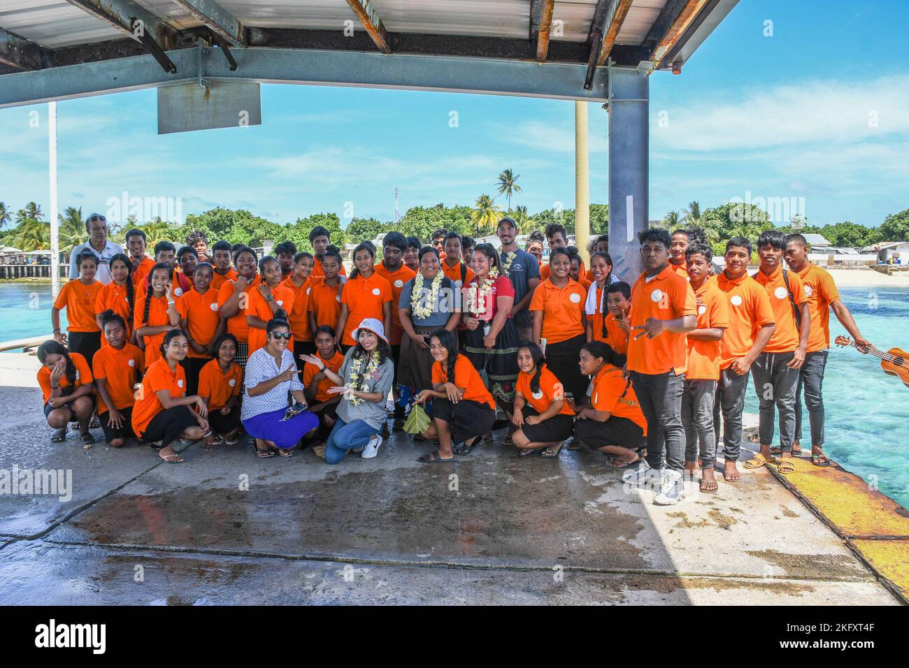 Mitarbeiter und Schüler der Enniburr High School und der Louis Berger Services gedenken einer Spende von Kwajalein am 13. Oktober 2022 mit einem Foto am Dock der Insel. Stockfoto
