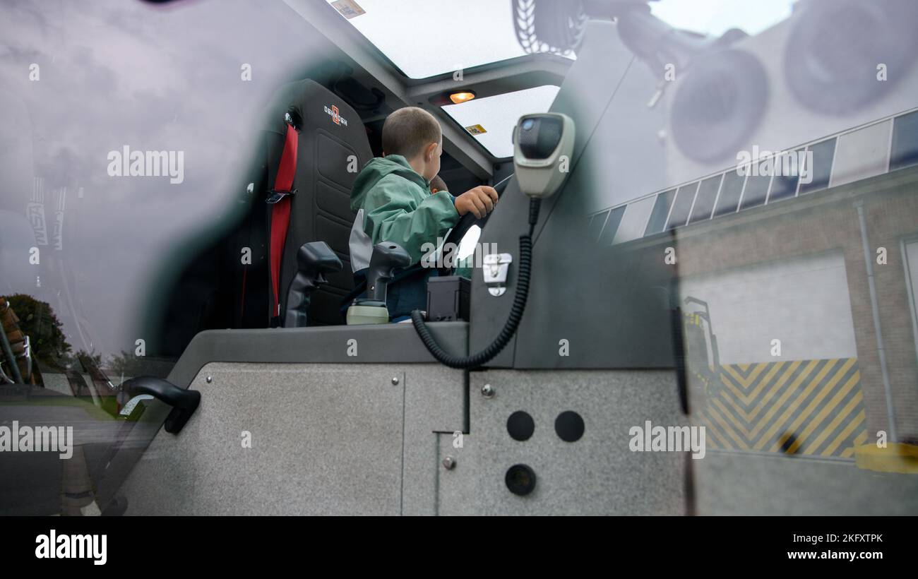 Ein belgischer Grundschüler hält das Lenkrad eines Feuerwehrwagens, während er die 424. Air Base Squadron Fire Station zur Brandverhütungswoche auf dem Luftwaffenstützpunkt Chièvres, Belgien, besucht, 13. Oktober 2022. Stockfoto