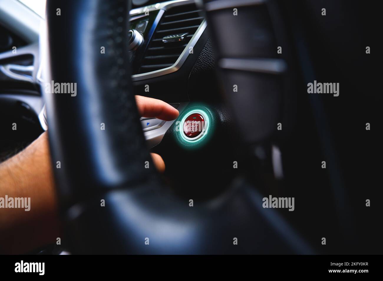 Der Fahrer drückt die Start-Stopp-Taste des Elektromotors mit einer grünen Anzeige Stockfoto