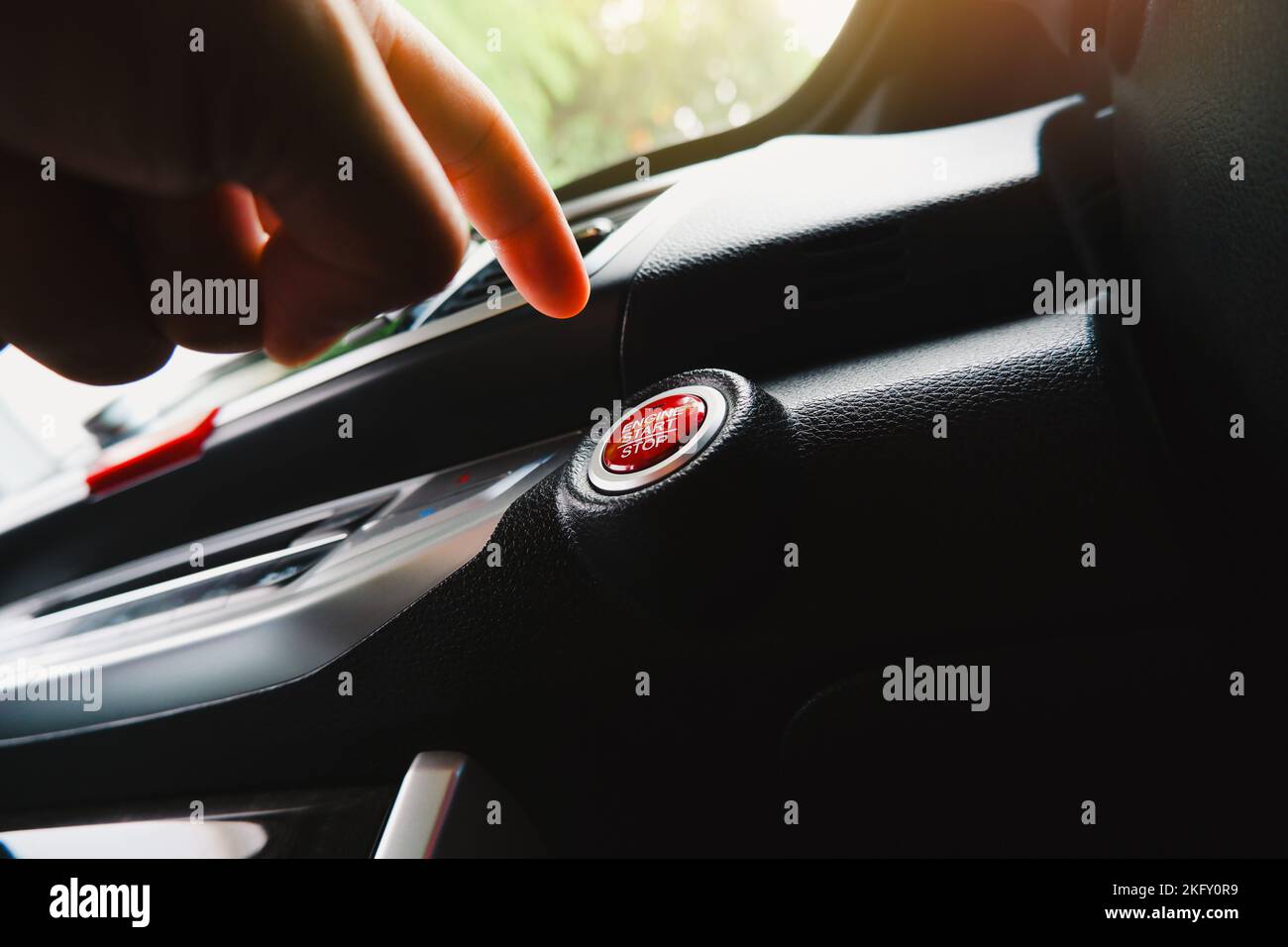 Der Fahrer drückt in einem Auto den Start-Stopp-Knopf des Elektromotors Stockfoto