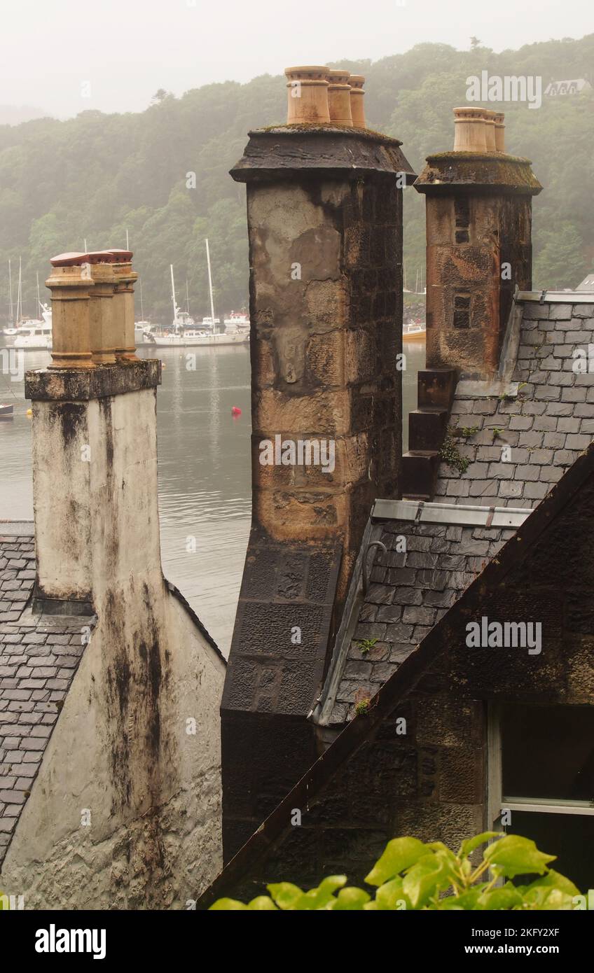 Alte Schornsteine auf alten Häusern über dem Hafen von Tobermory, Mull, Schottland, die alte Ziegelarbeiten und Schieferdächer zeigen Stockfoto