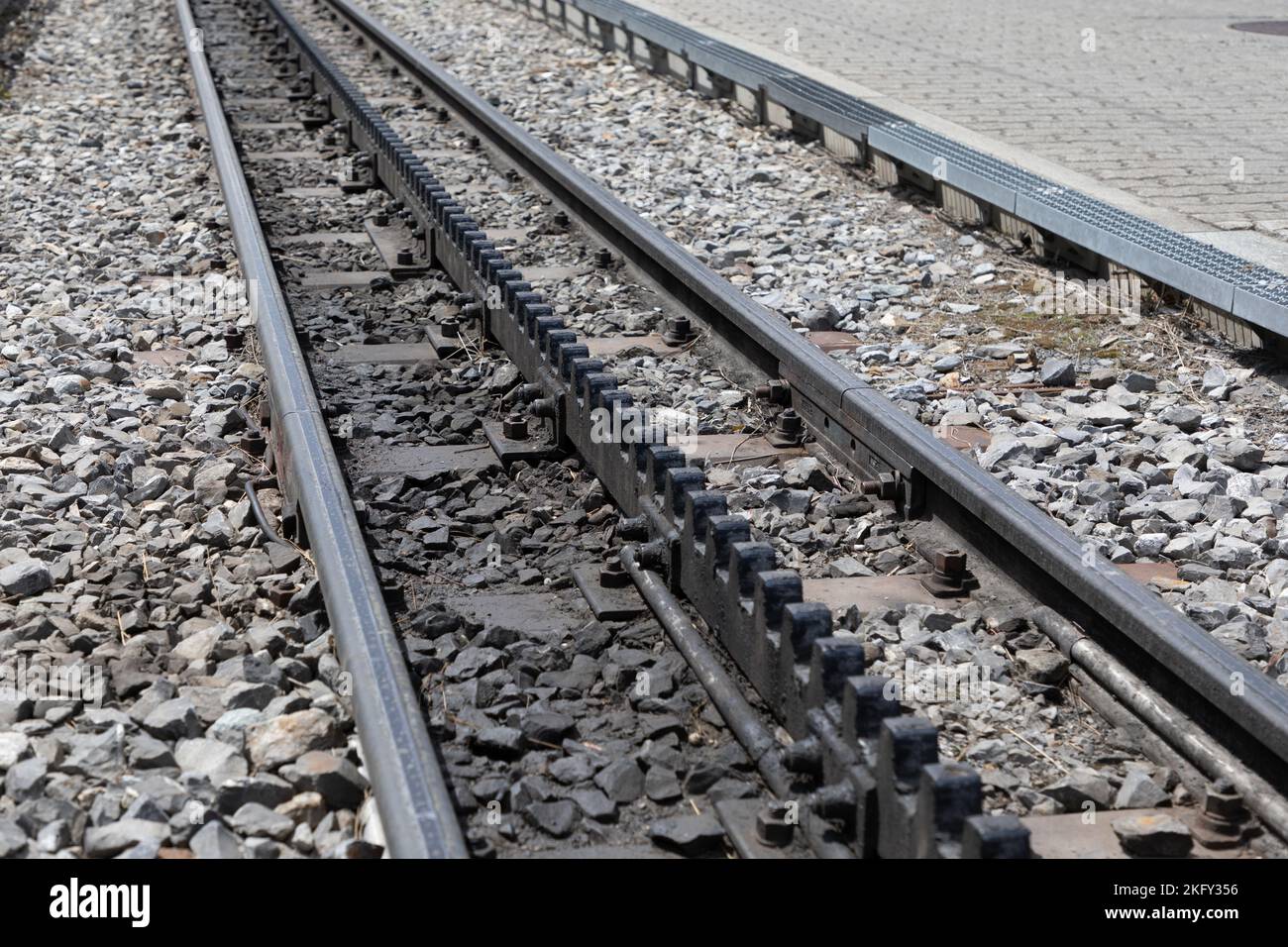 Diagonalansicht der Bahngleise mit einer dritten Zahnradspur in der Mitte. Typisch für die Eisenbahn in den Schweizer alpen. Stockfoto