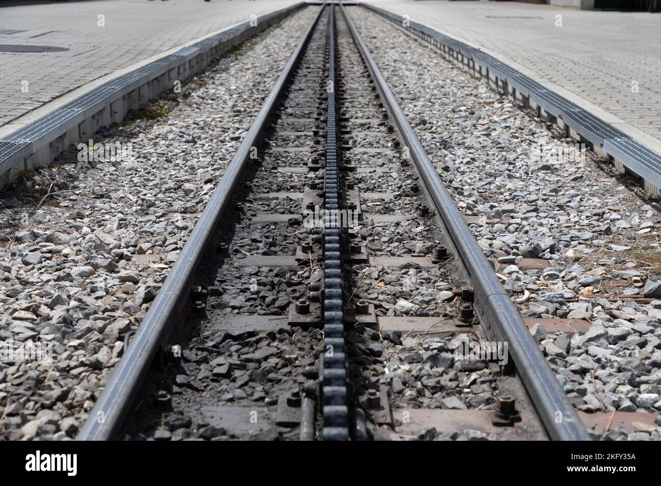 Selektiver Fokus, abnehmende Perspektive Bahngleise mit einer mittleren dritten Zahnradbahn, um die Züge an einem steilen Hang hochzuziehen. Stockfoto