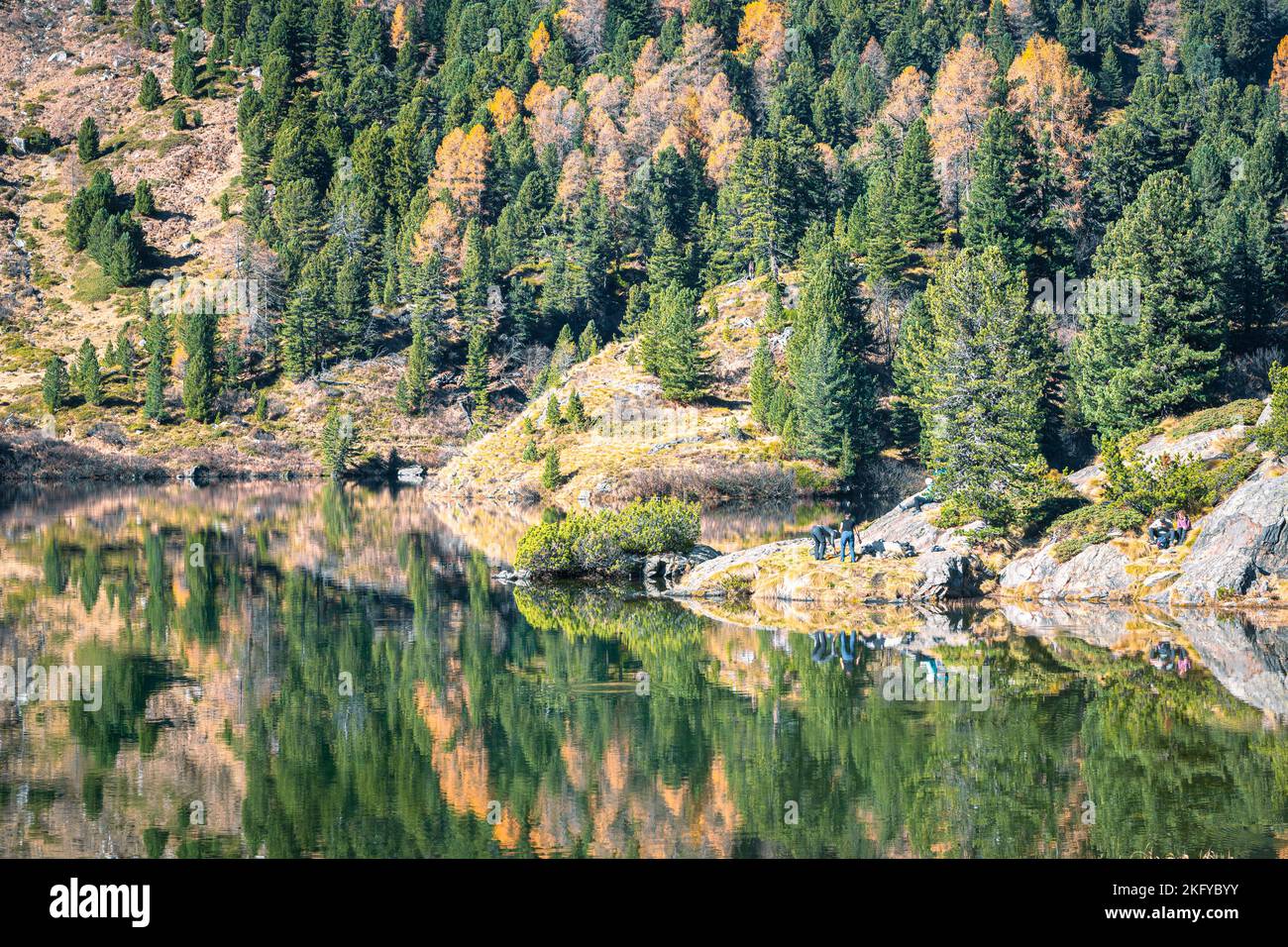 Die Menschen erholen sich am Ufer des idyllischen Cavloc-Sees, nahe dem Malojapass im Kanton Graubünden, Schweiz. Stockfoto