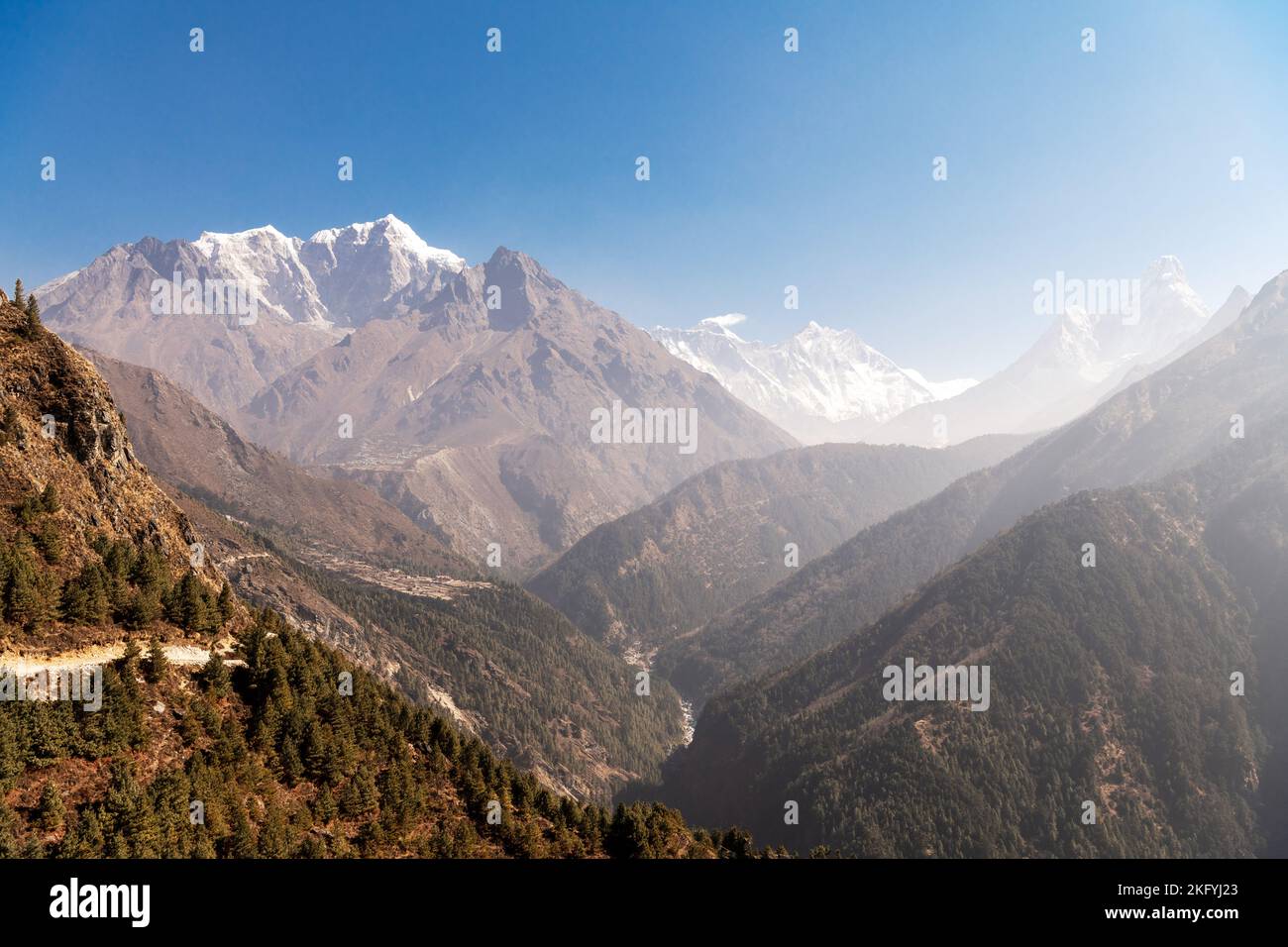 Erstaunliche Himalaya Berge bedeckt grünes Gras, hoher Wasserfall, schöner Weg, grüne Bäume, blauer Himmel mit gelber Sonne und Wolken in Nepal bei Sonnenuntergang Stockfoto