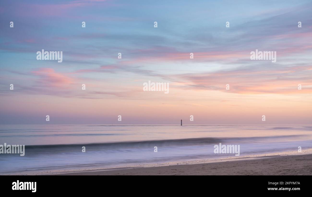 Schöner Sonnenuntergang am Meer. Ein isolierter Leuchtturm, der vor dem Ufer steht. rivedoux Strand auf der Insel Ré Stockfoto