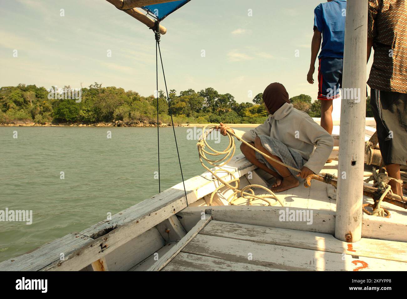 Die Bootsbesatzungen werden kurz vor Anker werfen, während ein gemietetes Boot auf der Küste der Insel Handeuleum, einem Teil des Ujung Kulon Nationalparks in Pandeglang, Banten, Indonesien schwimmt. Stockfoto