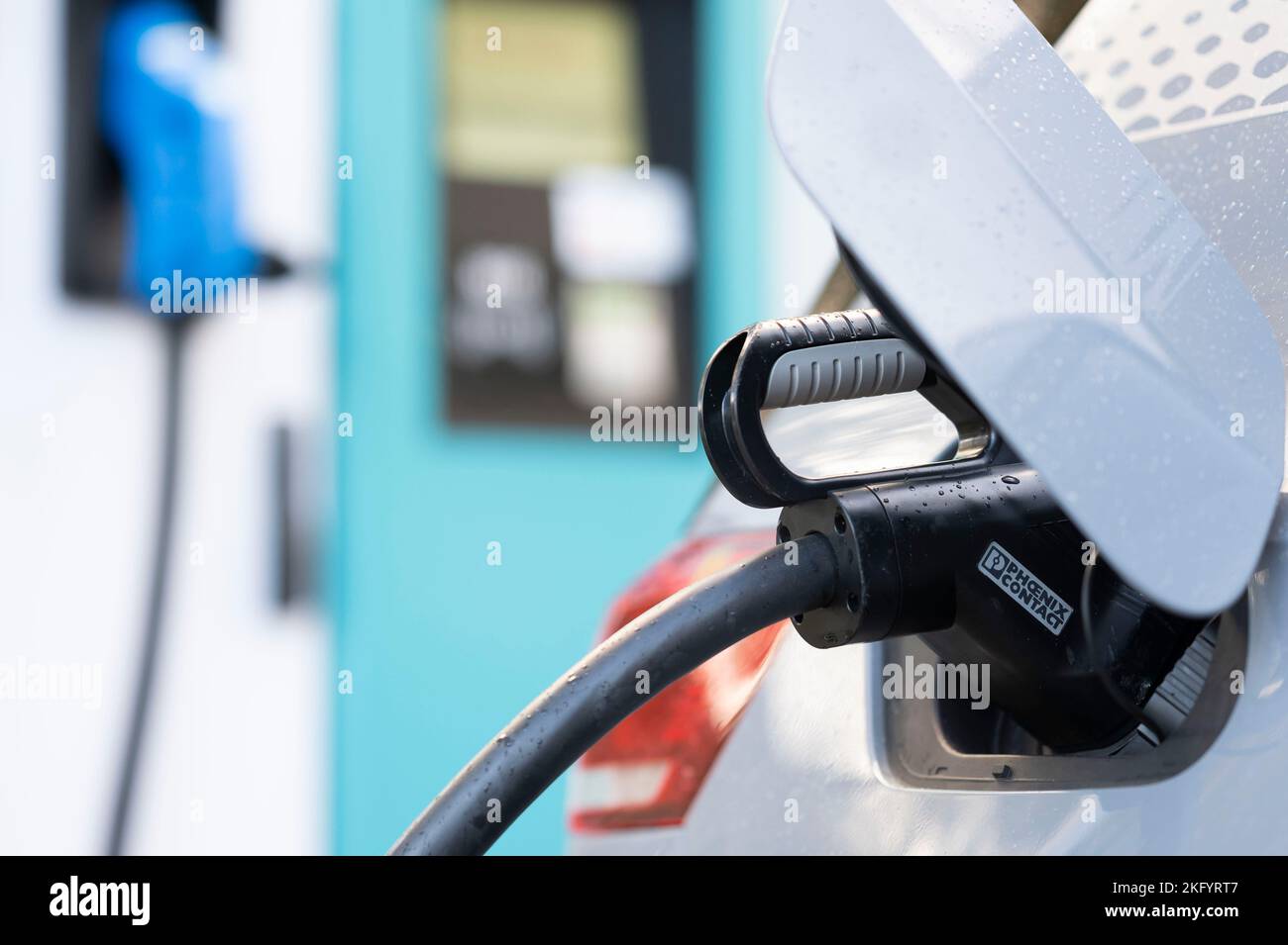 Eine Nahaufnahme eines Ladesteckers eines Elektroautos, der mit einem Auto verbunden ist. Stockfoto