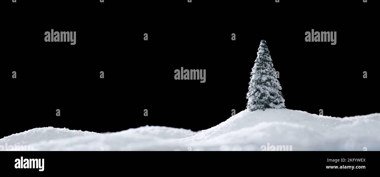 Winterliche Landschaft mit einem einzigen Baum auf glitzerndem weißem Schnee driftet isoliert auf schwarzem Stockfoto