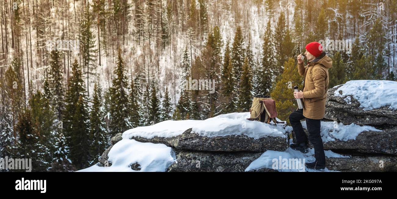 Ein Mann Tourist mit einem Telefon in der Hand auf der Oberseite weit weg von der Zivilisation vor dem Hintergrund eines verschneiten Waldes. Das Konzept von Aktivität und Verfügbarkeit Stockfoto