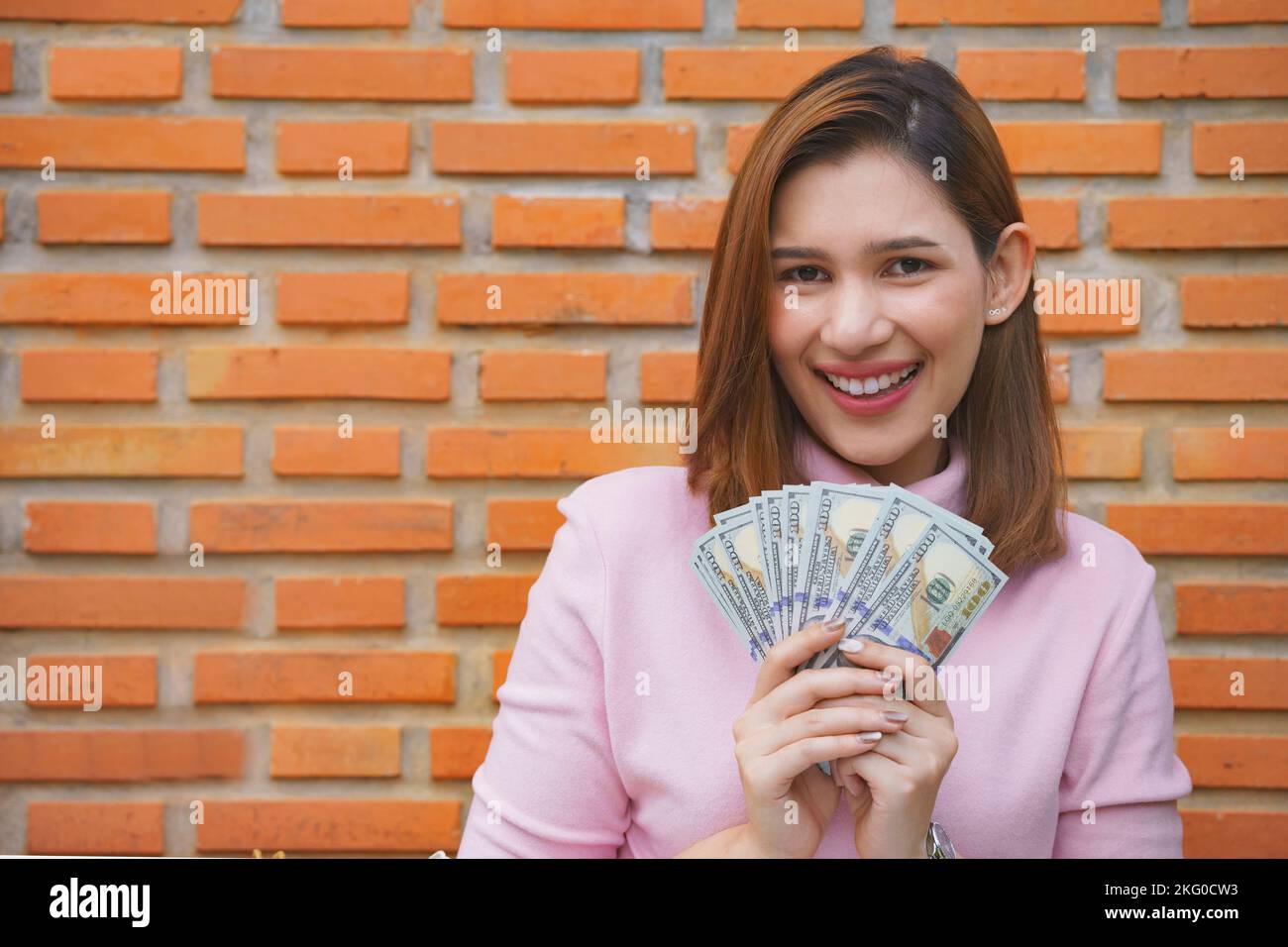 Nahaufnahme, junge Frau lächelt zufrieden, als sie Dollar hält. Stockfoto