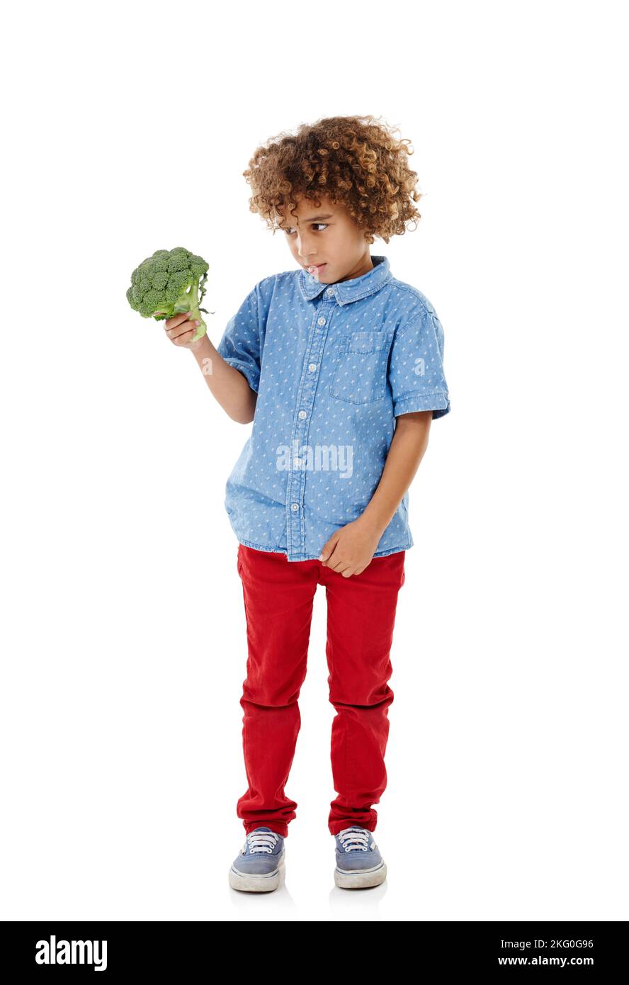 Wie wäre es mit einem Burger stattdessen. Studioaufnahme eines niedlichen kleinen Jungen, der vor weißem Hintergrund zögerlich auf Brokkoli schaut. Stockfoto