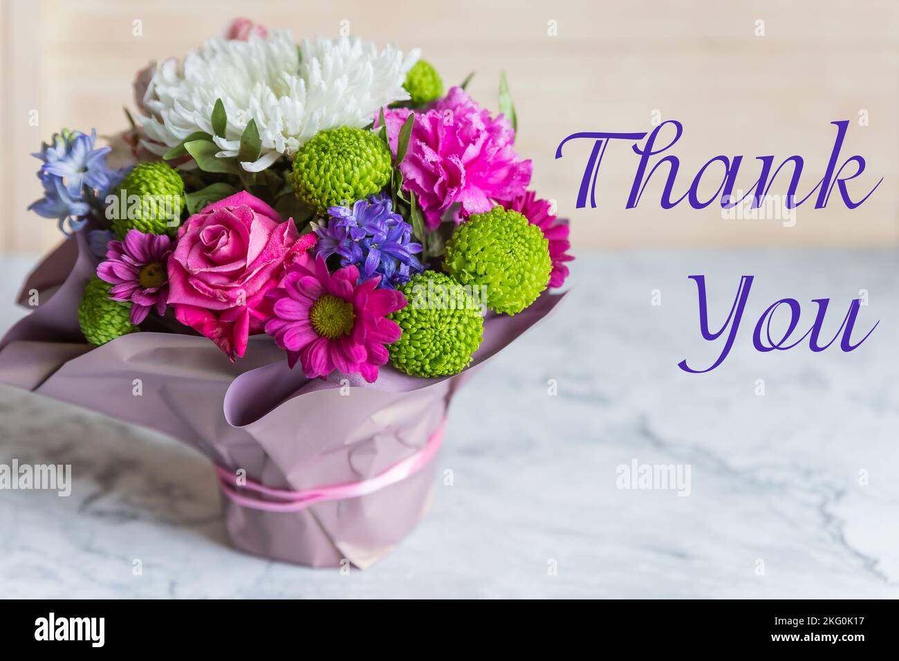 Blumenstrauß mit rosa Rose und Schriftzug Danke, englisch. Leuchtender Strauß von Rosen, Lisianthus, Alstroemeria und anderen Blumen. Präsent für den Frühling Stockfotografie