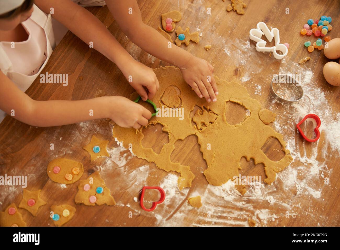 Draufsicht, Kinderhände und Backen mit Ausstechformen in Haus- oder Familienküche mit Gebäck, Eiern oder Süßigkeiten. Kinder, Mädchen oder Geschwister Stockfoto