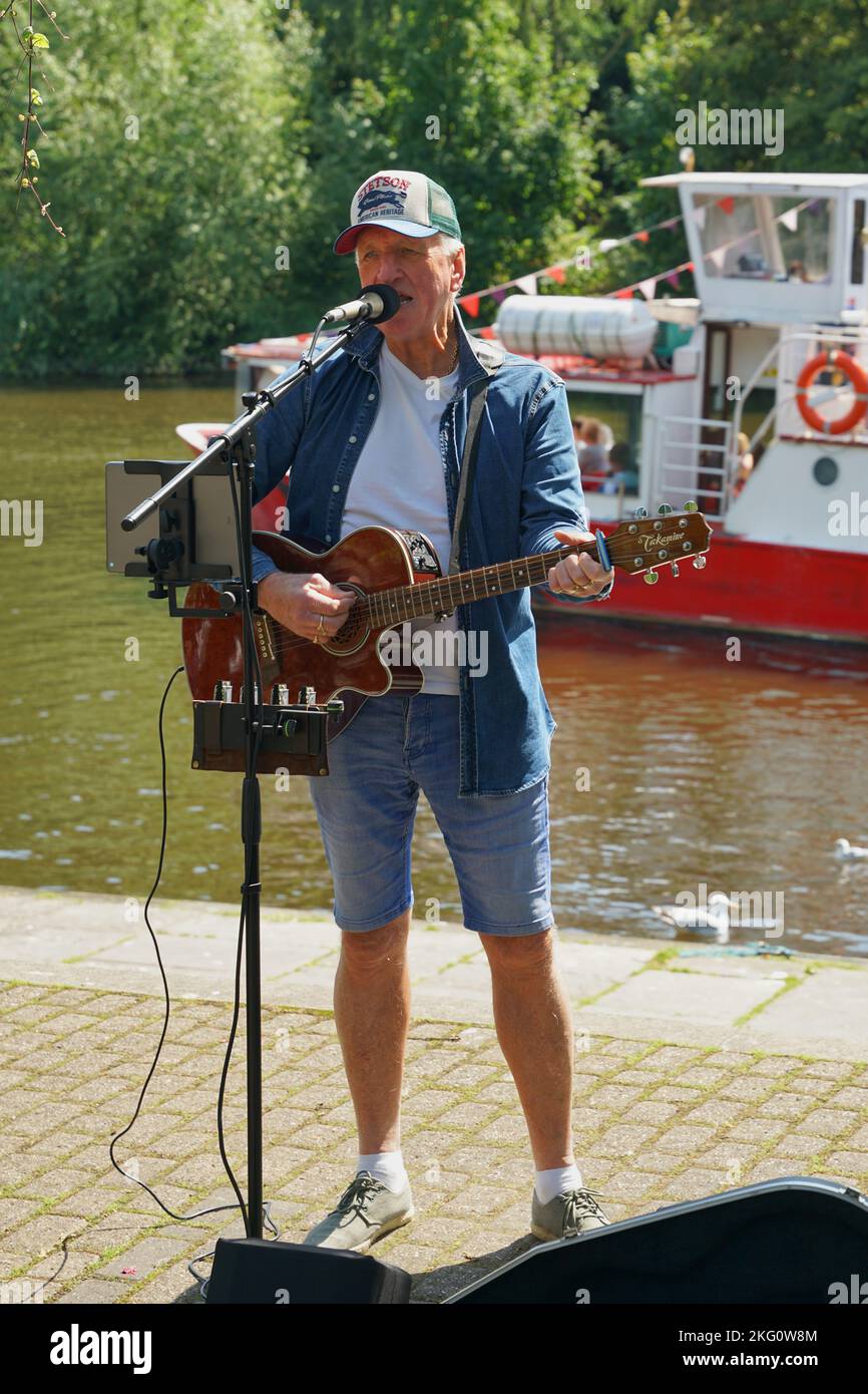 Ein Mann, der in einem Touristengebiet am Chester Lake, Großbritannien, singt und Gitarre spielt Stockfoto