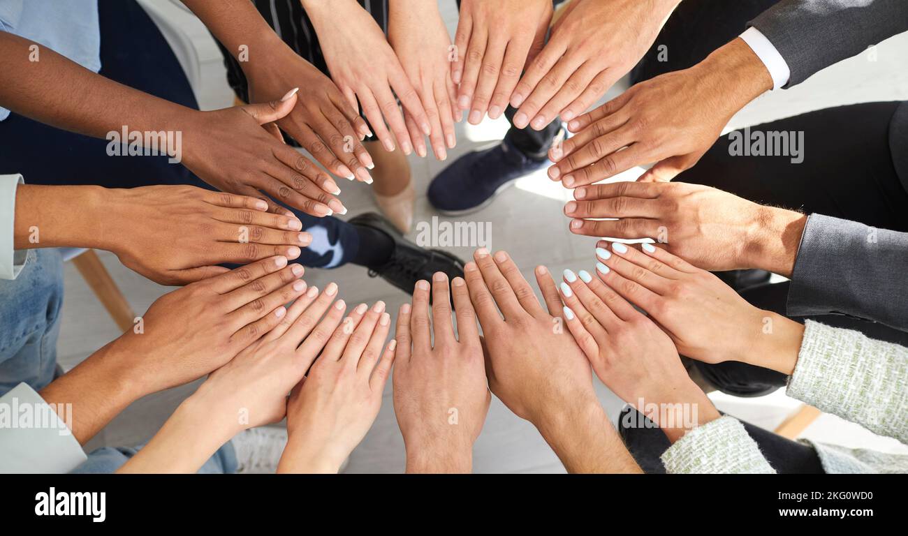 Ein vielfältiges Team von Menschen, das sich im Kreis zusammenschließt, um Teamarbeit und Unterstützung zu veranschaulichen Stockfoto