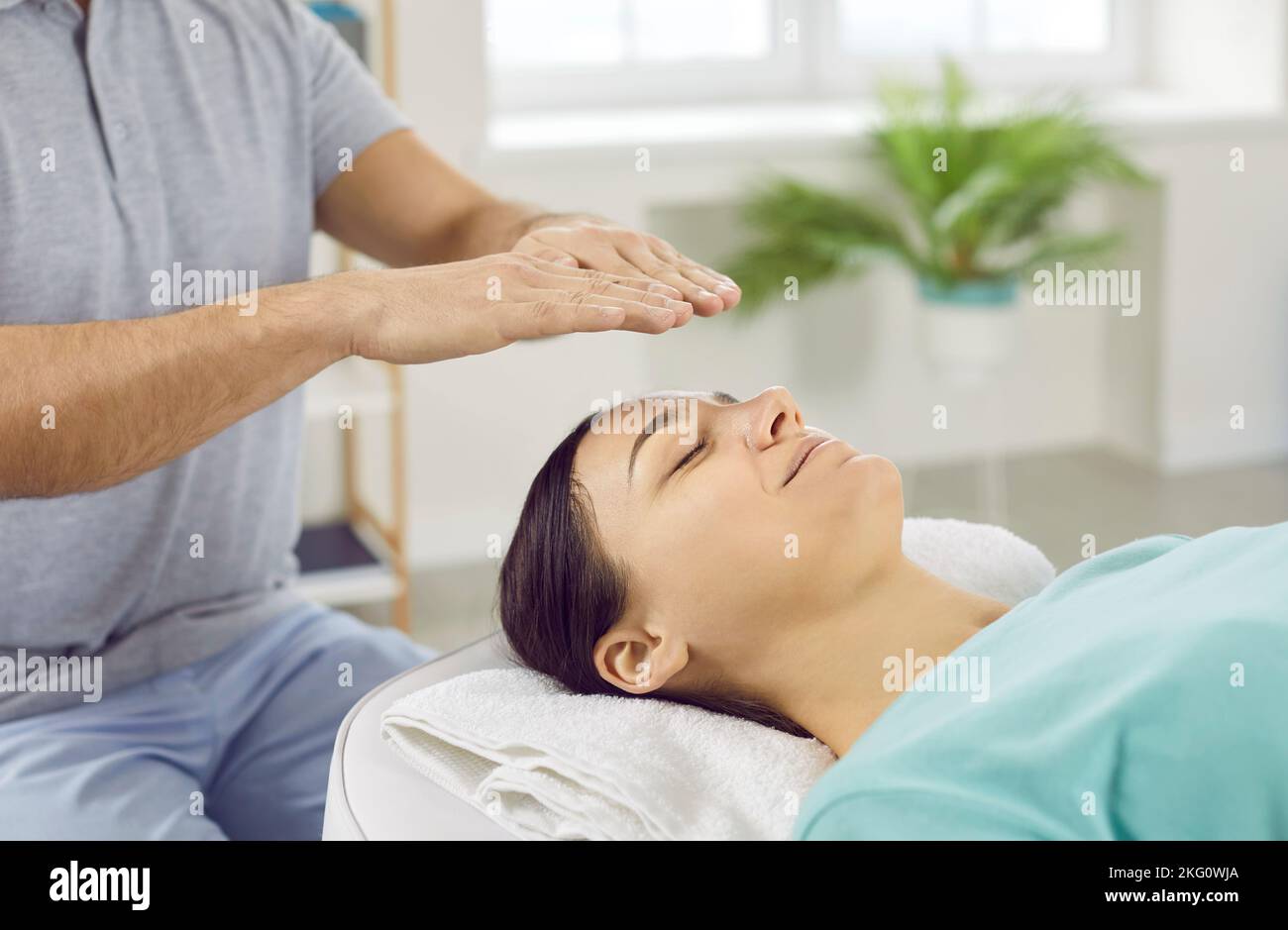 Frau entspannt sich und gewinnt Energie während der ganzheitlichen Therapie-Sitzung mit Reiki Heiler Stockfoto