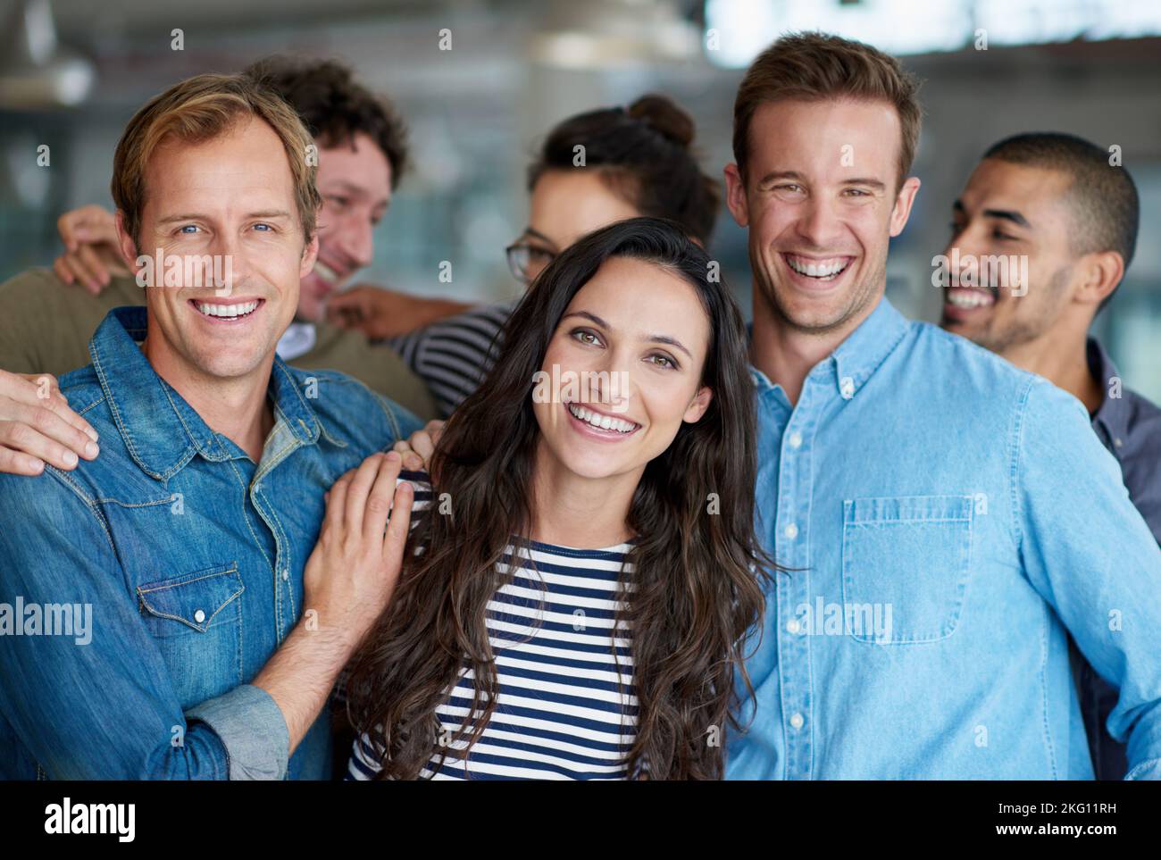 Wir haben eine tolle Arbeitsatmosphäre. Eine lächelnde Gruppe von Mitarbeitern steht in einem Büro. Stockfoto