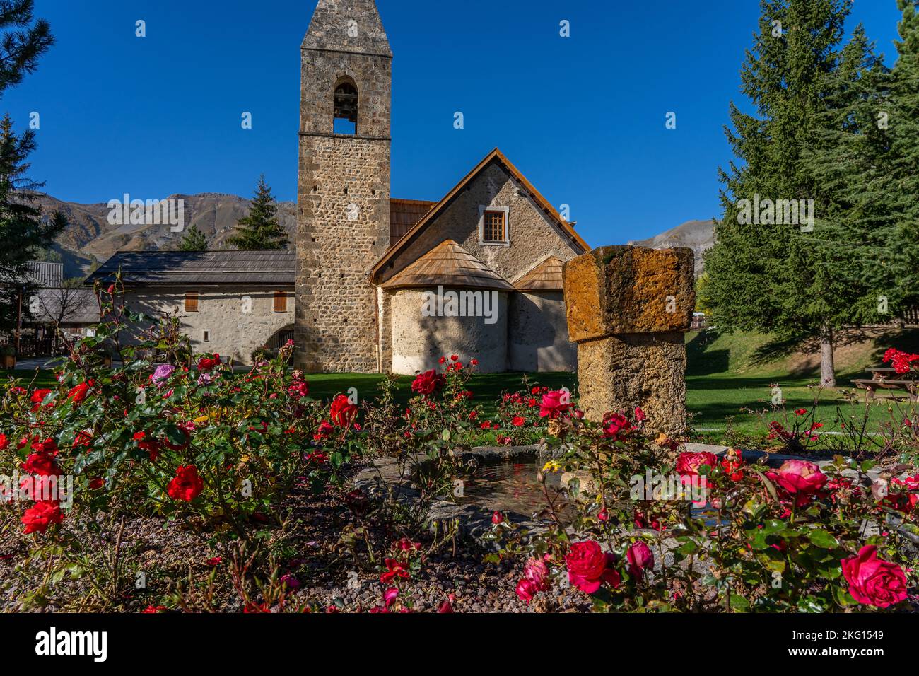 Rosengarten in der Nähe der Kirche in der französischen Bergstadt. Ländliche Landschaft in der Nähe eines berühmten französischen Resorts Auron, Europa. Hochwertige Fotos Stockfoto