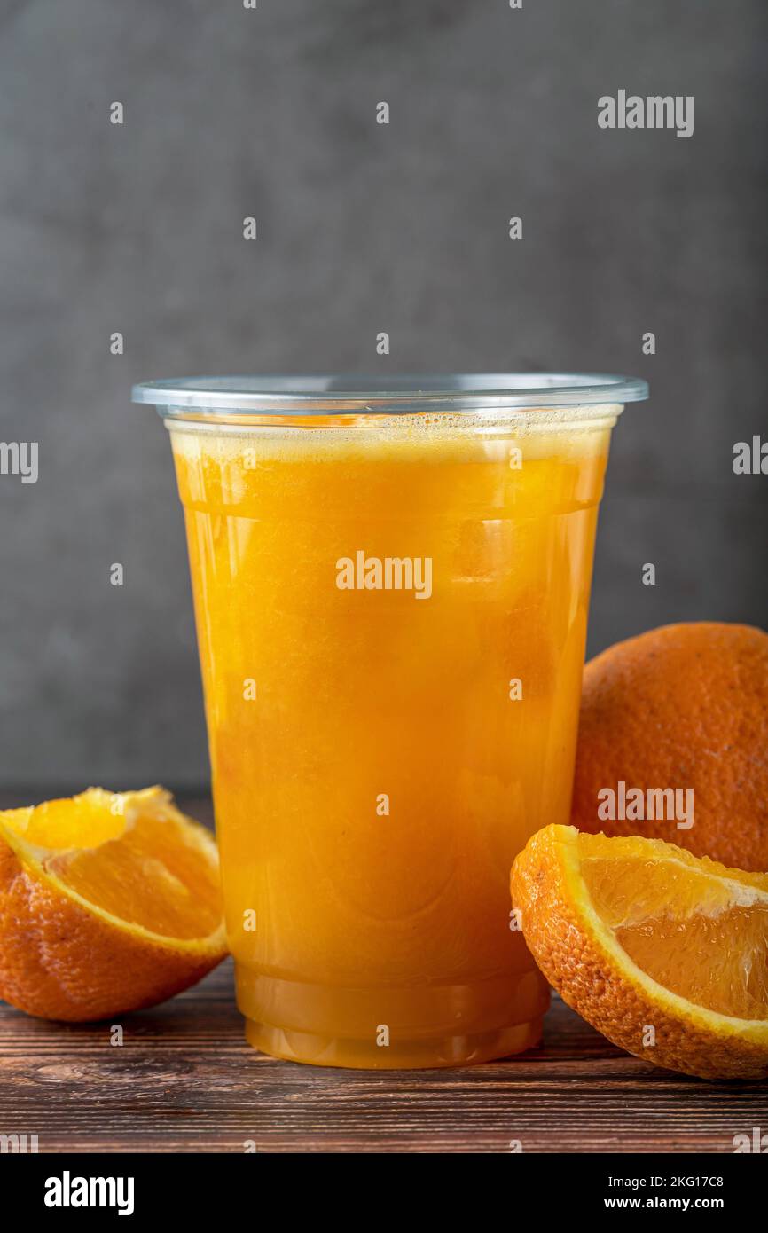 Frisch gepresster Orangensaft mit Eiswürfeln auf Holztisch Stockfoto