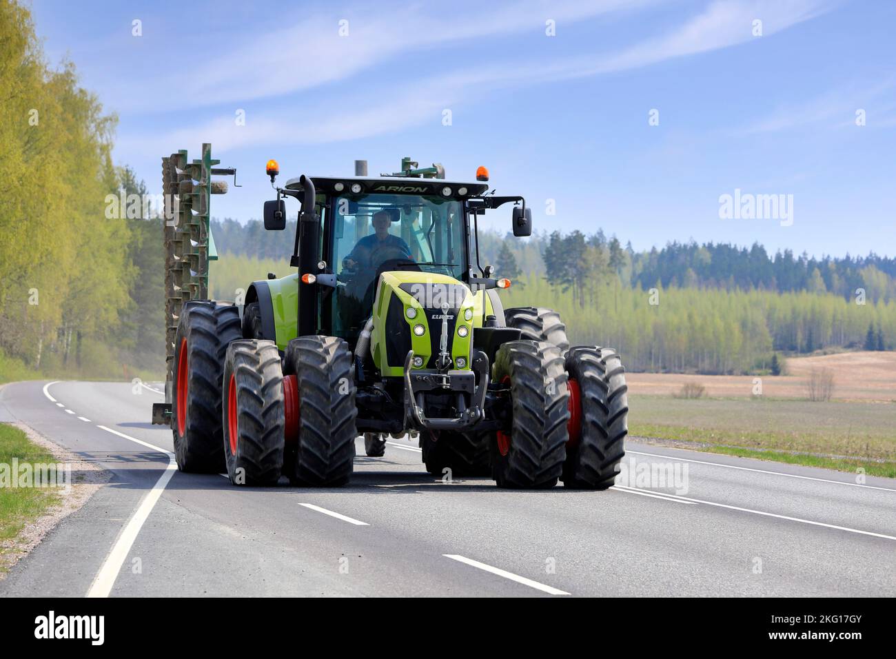 Großer grüner Claas Arion 640 Traktor mit Doppelreifen, der an einem sonnigen Maitag landwirtschaftliche Geräte auf der Straße zieht. Salo, Finnland. 13.Mai 2021. Stockfoto
