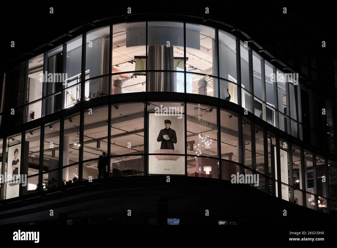 Eine dunkle Nacht in Berlin - Berliner Nachtarchitektur. Gewerbliches architektonisches Gebäude zur Abendzeit, Einkaufszentrum mit Anzeige im Fenster. Stockfoto