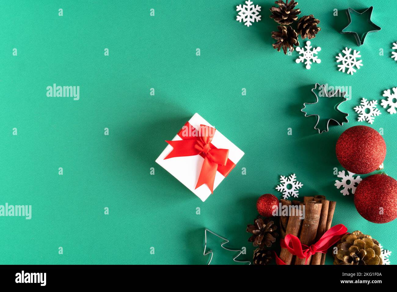Weihnachtliche Naturdekorationen aus Holz, rote Kugeln, Geschenkbox und Notizblock auf grünem Hintergrund. Weihnachtsgruß-Design. Flach liegend, Draufsicht, Kopierbereich. Das Konzept eines Urlaubs, Verkauf, Neujahr. Stockfoto