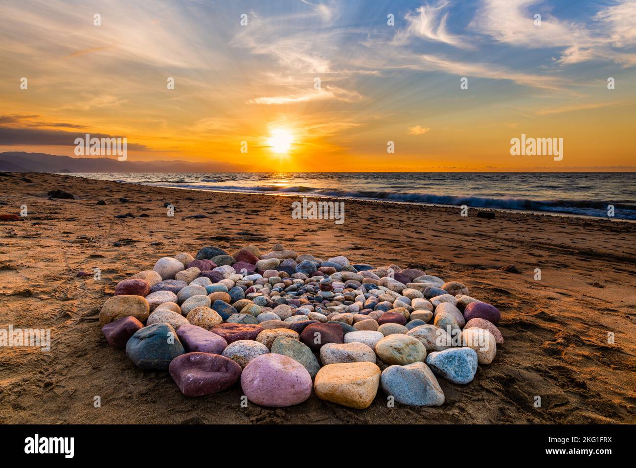 Während des Sonnenuntergangs am Strand werden heilige Ritualsteine für spirituelle Zeremonien in Einem Kreis angeordnet Stockfoto